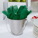 A white bucket filled with emerald green Creative Converting plastic forks.