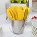 A bucket of Creative Converting School Bus Yellow plastic knives.