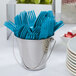 A bucket of blue plastic forks.