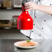 A chef using a Cres Cor red ceiling infrared bulb to warm food above a table.