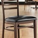 A Lancaster Table & Seating wooden chair with a black padded seat.