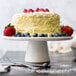 A white cake with strawberries and blueberries on a 10 Strawberry Street Whittier white porcelain cake stand.