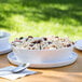 A white melamine bowl filled with pasta on a table with two white plates.