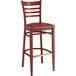 A red metal Lancaster Table & Seating bar stool with a mahogany wood grain and burgundy vinyl cushion.