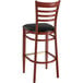 A Lancaster Table & Seating metal ladder back bar stool with a black vinyl seat.