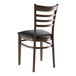 A Lancaster Table & Seating metal ladder back chair with dark walnut wood grain finish and black vinyl seat.