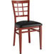A Lancaster Table & Seating Spartan Series chair with mahogany wood grain finish and a black vinyl cushion.