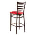 A metal ladder back bar stool with a dark walnut wood grain finish and a red vinyl seat.