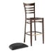 A Lancaster Table & Seating brown metal ladder back bar stool with a black vinyl seat.