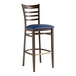 A metal ladder back bar stool with a dark walnut wood grain finish and a navy vinyl seat.