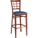 A Lancaster Table & Seating Spartan Series metal bar stool with mahogany wood grain finish and navy vinyl seat.