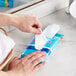 A person using a SC Johnson Windex glass wipe to clean a sink.