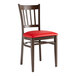 A Lancaster Table & Seating wooden slat back chair with a dark walnut finish and red vinyl seat.