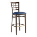 A Lancaster Table & Seating Spartan Series bar stool with dark walnut wood grain finish and navy vinyl seat.