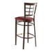 A Lancaster Table & Seating metal bar stool with a burgundy vinyl seat and a dark walnut wood grain finish.