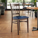 A Lancaster Table & Seating wooden chair with navy vinyl seat at a table in a restaurant.