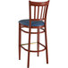 A wooden bar stool with a mahogany wood grain finish and navy vinyl seat.