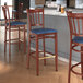 A Lancaster Table & Seating Spartan Series bar stool with navy vinyl seat and mahogany wood grain finish.