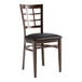 A Lancaster Table & Seating metal window back chair with dark walnut wood grain finish and a black cushion.