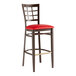 A Lancaster Table & Seating metal bar stool with a dark walnut frame and red vinyl seat.