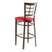 A Lancaster Table & Seating metal bar stool with red vinyl seat and window back.