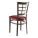 A Lancaster Table & Seating metal window back chair with a burgundy vinyl seat.