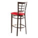 A Lancaster Table & Seating metal restaurant bar stool with a red vinyl seat and window back.