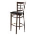 A Lancaster Table & Seating metal window back bar stool with a black vinyl seat.