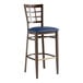 A Lancaster Table & Seating metal bar stool with dark walnut wood grain and a navy vinyl seat.