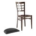 A Lancaster Table & Seating Spartan series brown wooden chair with a black vinyl seat.