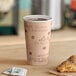 A Choice Caf&#233; print paper hot cup filled with coffee on a table with a pastry.