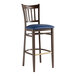 A Lancaster Table & Seating Spartan Series bar stool with a dark walnut wood grain finish and navy vinyl seat.