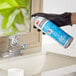 A hand in a black glove using 3M Stainless Steel Cleaner on a sink.