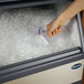 A hand scooping ice from a Follett undercounter ice machine.