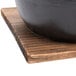 A black Thunder Group cast iron noodle bowl on a wooden base.