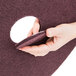 A hand holding a 3M Scotch-Brite surface preparation floor pad with a hole in it.