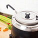 A Vollrath Jacob's Pride ladle with a black handle in a pot of vegetables.