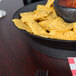 A bowl of chips and salsa in a charcoal deli server.