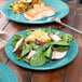 A Fiesta® luncheon plate with salad and fish on a table with a fork.