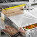 A person using Choice aluminum foil to cover food in a container.