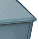 A blue metal Watts grease trap with a lid on a metal surface.