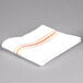 A folded white cloth napkin with orange stripes.