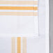 A white and gold striped cloth napkin with a close up of the fabric.