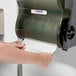 A person's hand using a Lavex paper towel dispenser.