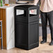 A person standing next to a black Commercial Zone PolyTec waste container.