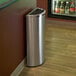 A stainless steel Commercial Zone Precision half round trash receptacle next to a wall.