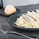 A black Hall China oval platter with pasta, chicken, and bread.