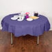 A table with a purple Creative Converting OctyRound tablecloth, plates, and utensils.