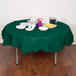 A table with a Hunter Green OctyRound table cover, plates, and cups.