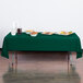 A table with food covered by a hunter green Creative Converting plastic table cover.